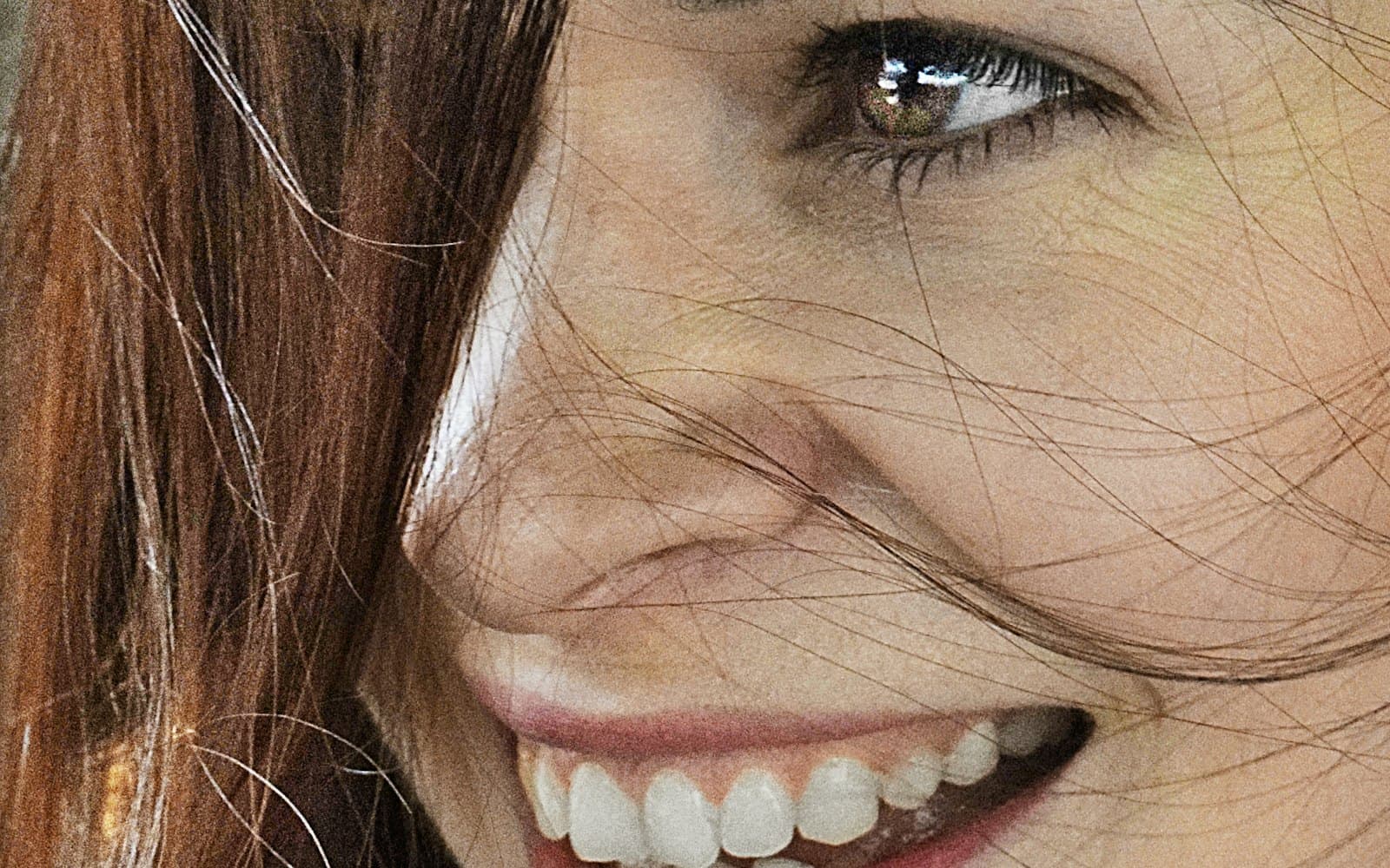 Close-up of a smiling face with freckles and fine skin texture in daylight