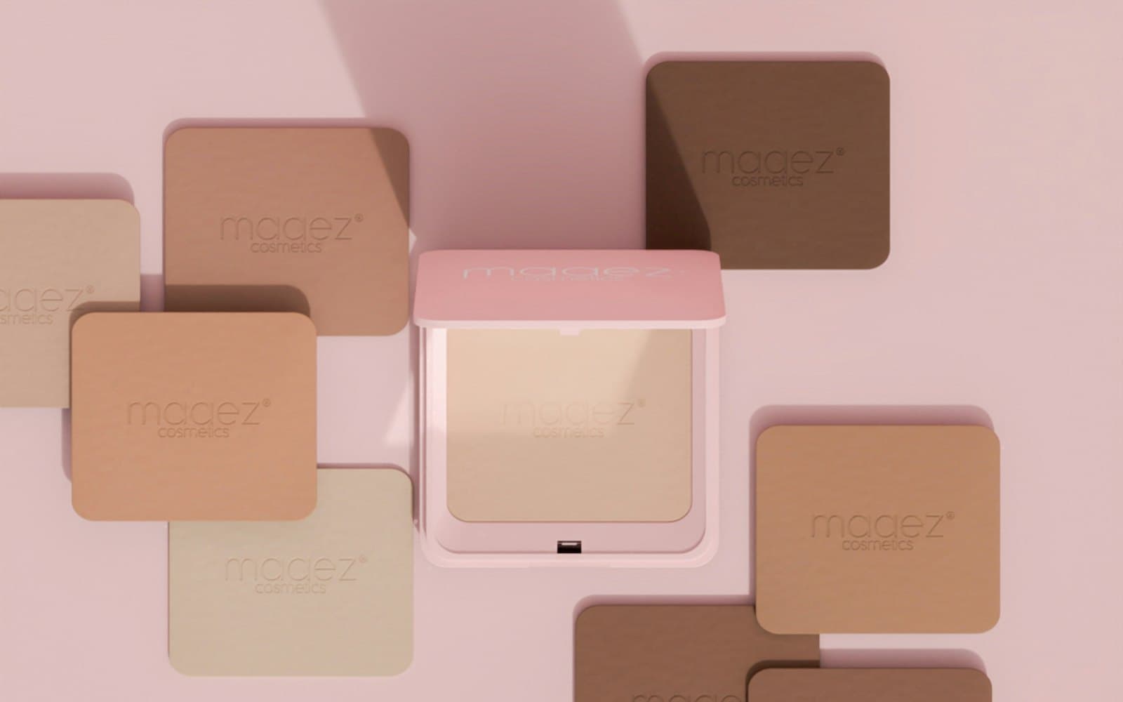 Compacts of powder in a range of skin shades laid out on pink
